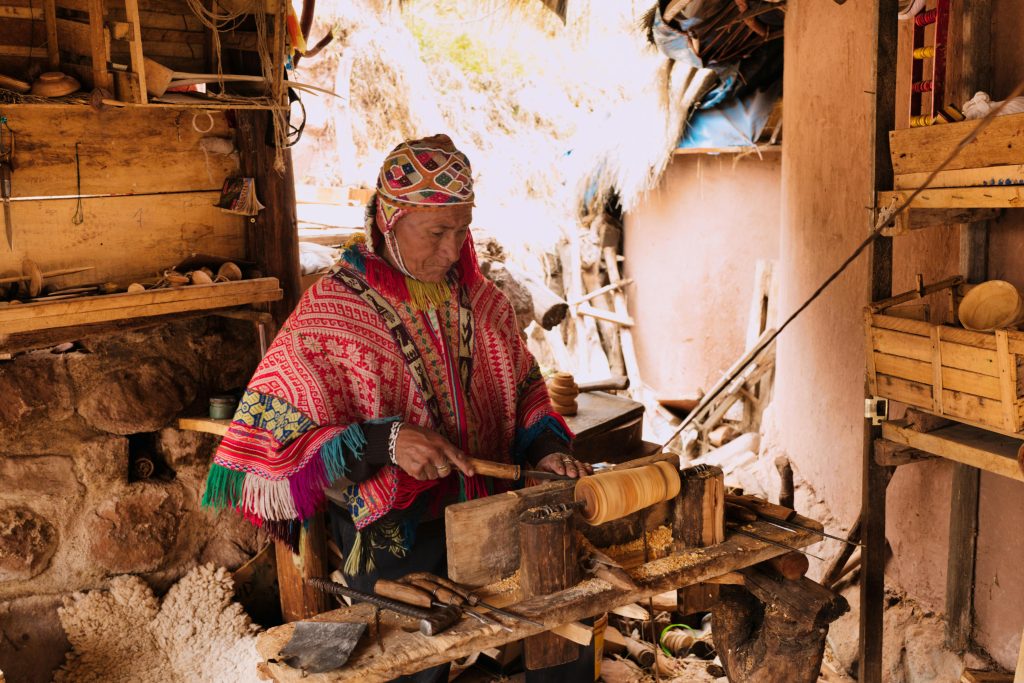 A skilled artisan in Peru crafts wood in a traditional rural workshop setting.